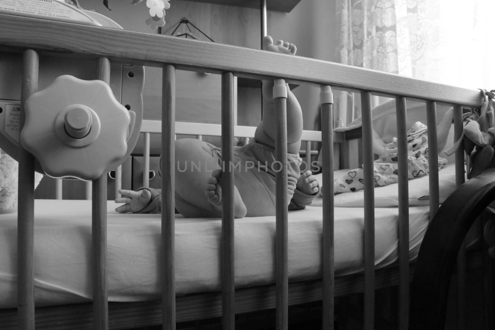 Baby, infant feet sticking out through the rails of a crib, cot, black and white photo, beautiful background for card,  banner, wallpaper design