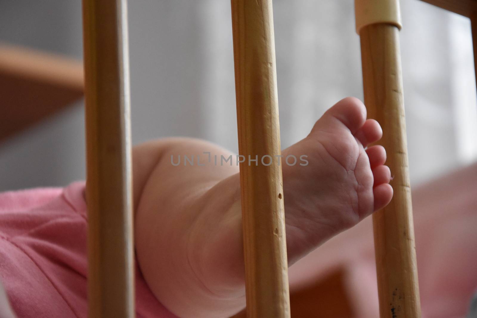 Baby, infant feet sticking out through the rails of a crib, cot, beautiful background for card,  banner, wallpaper design 