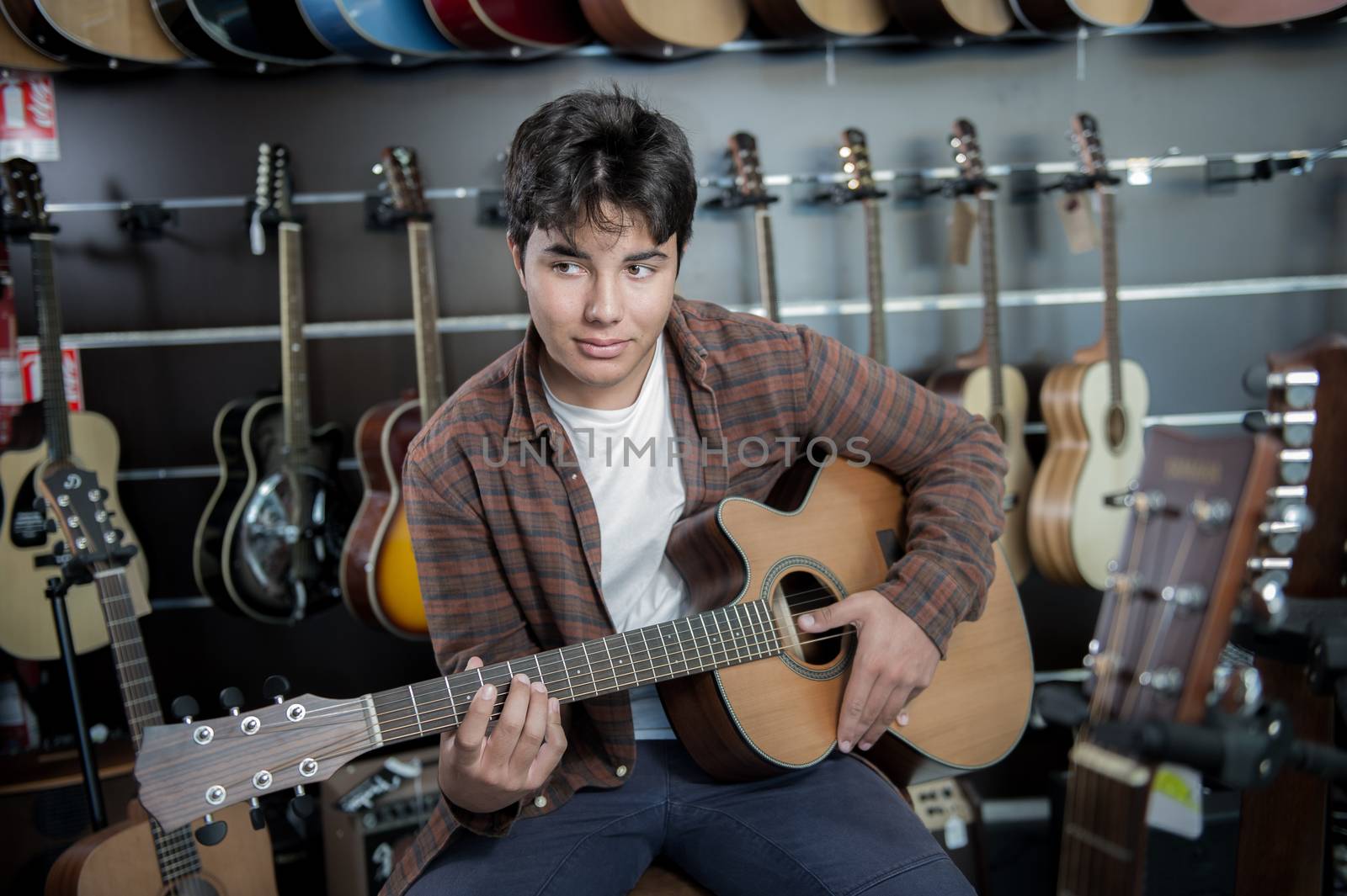 Young man playing the guitar in a shop, France