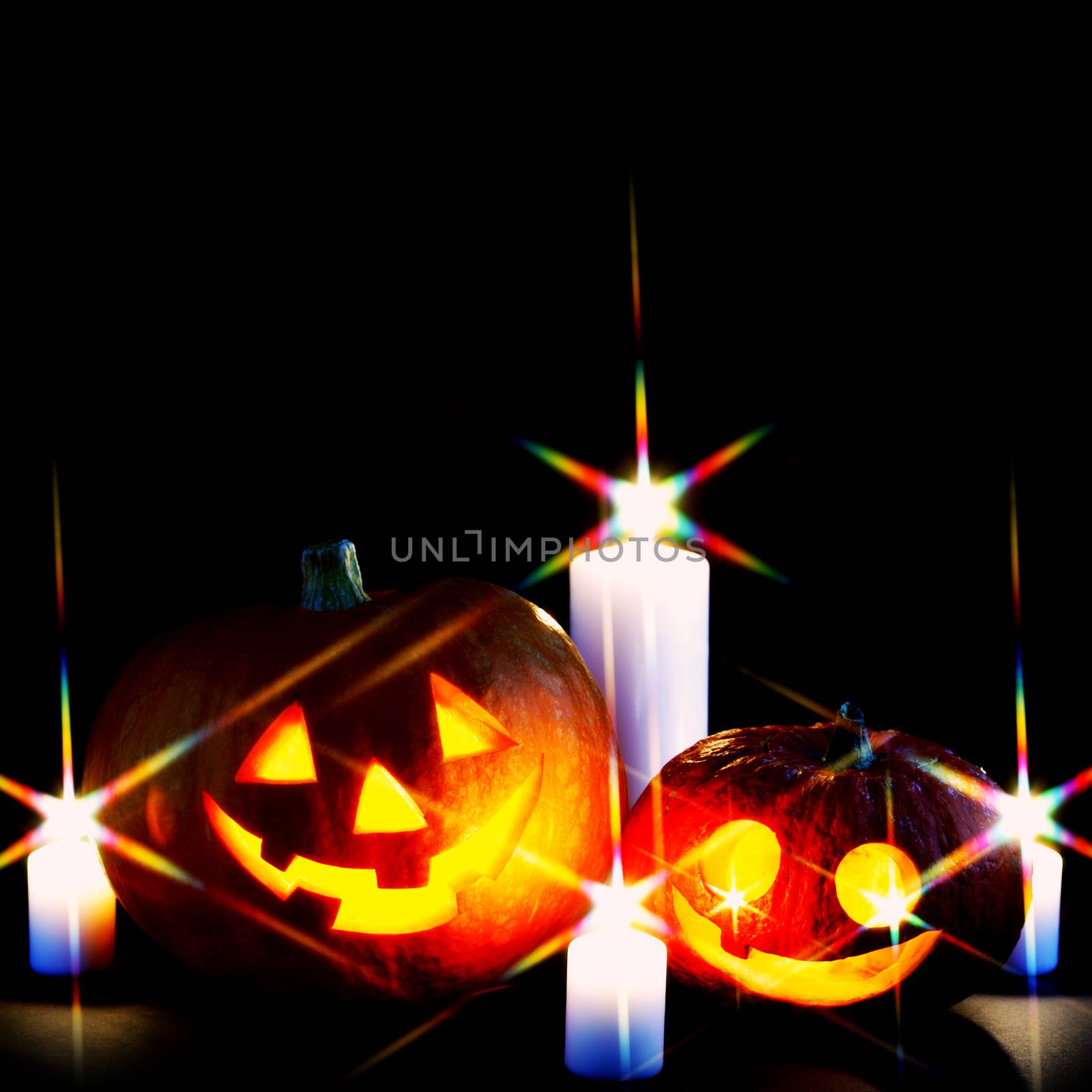 Funny Halloween pumpkins and burning candles on black background