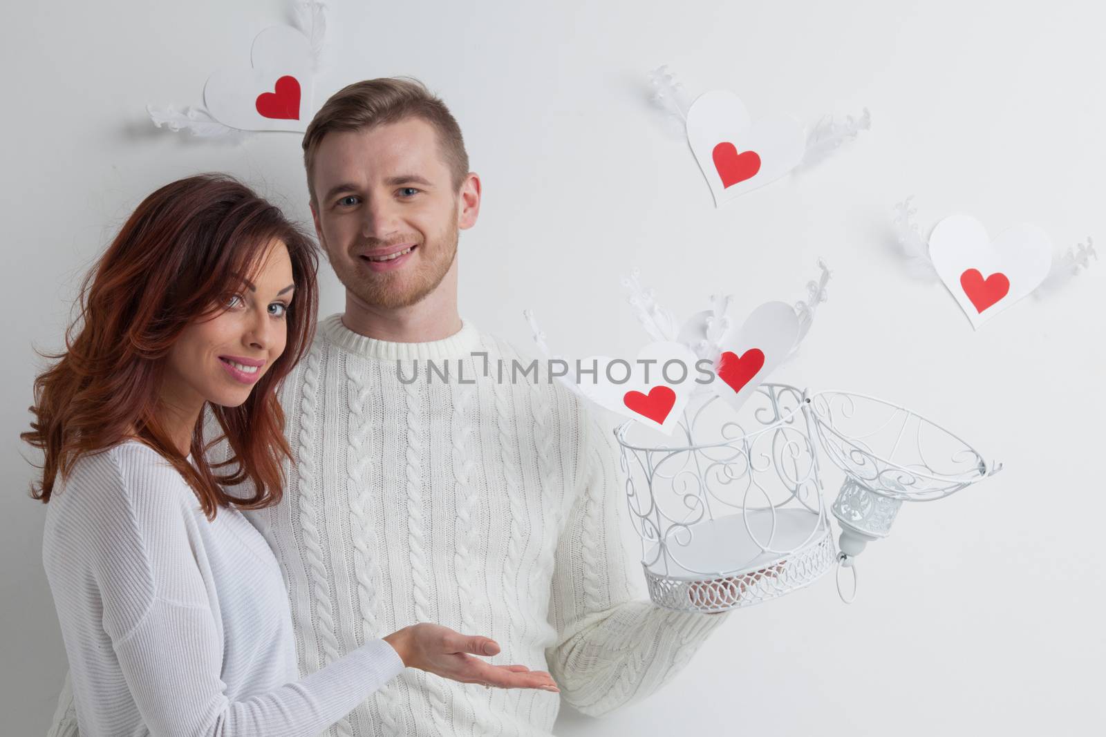 Young couple with winged hearts flying from the cage, Valentines day concept