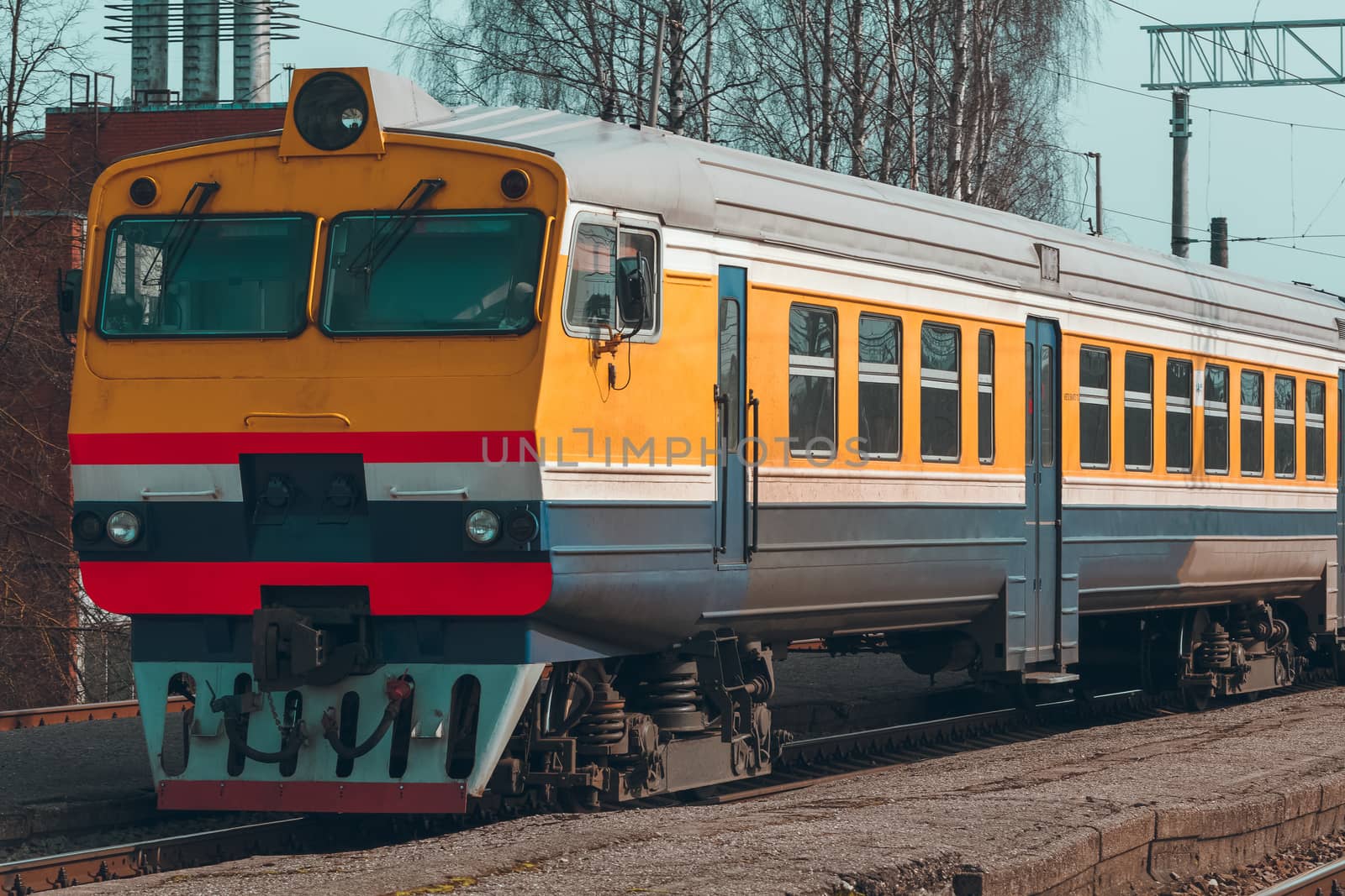 Old yellow passenger diesel train moving at the terminal