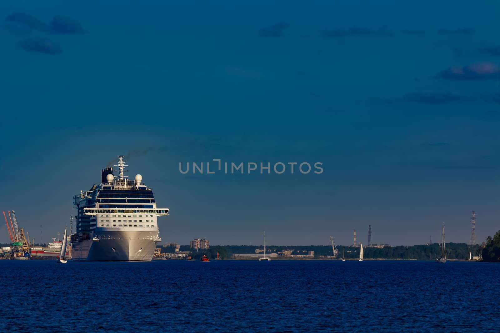 Giant white passenger ship moving past the port on a clear day