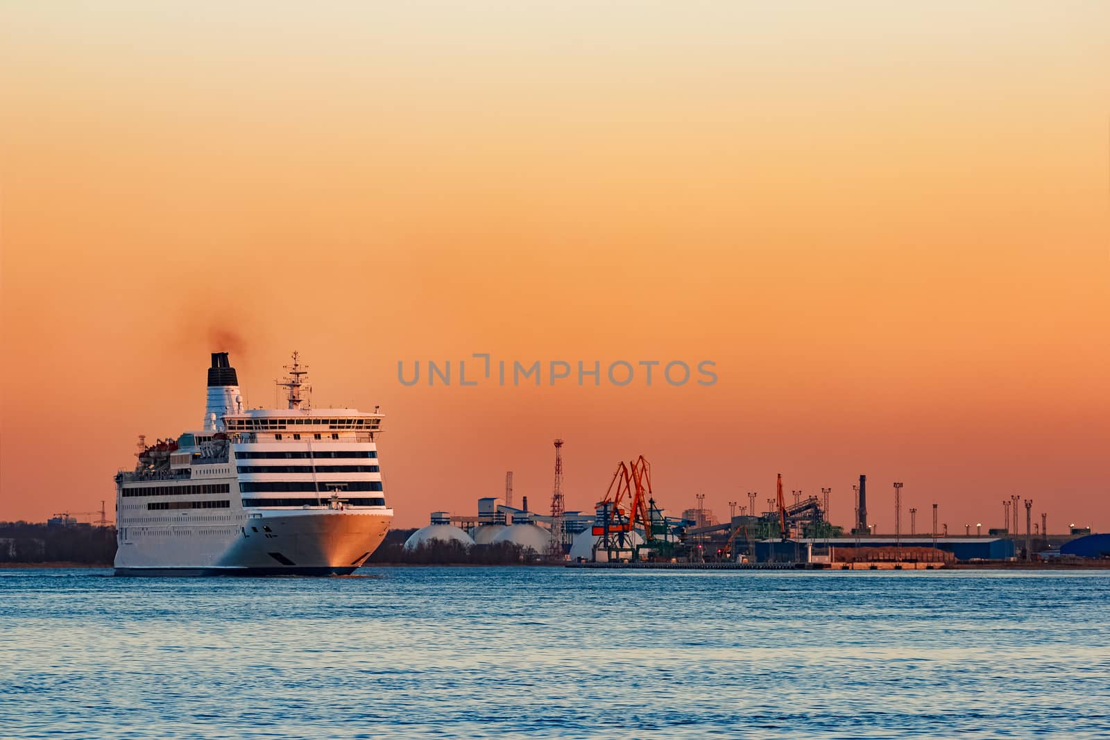 White passenger ship moving against the orange sunset sky