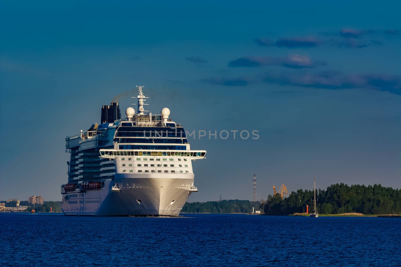 Giant white passenger ship moving past the port on a clear day