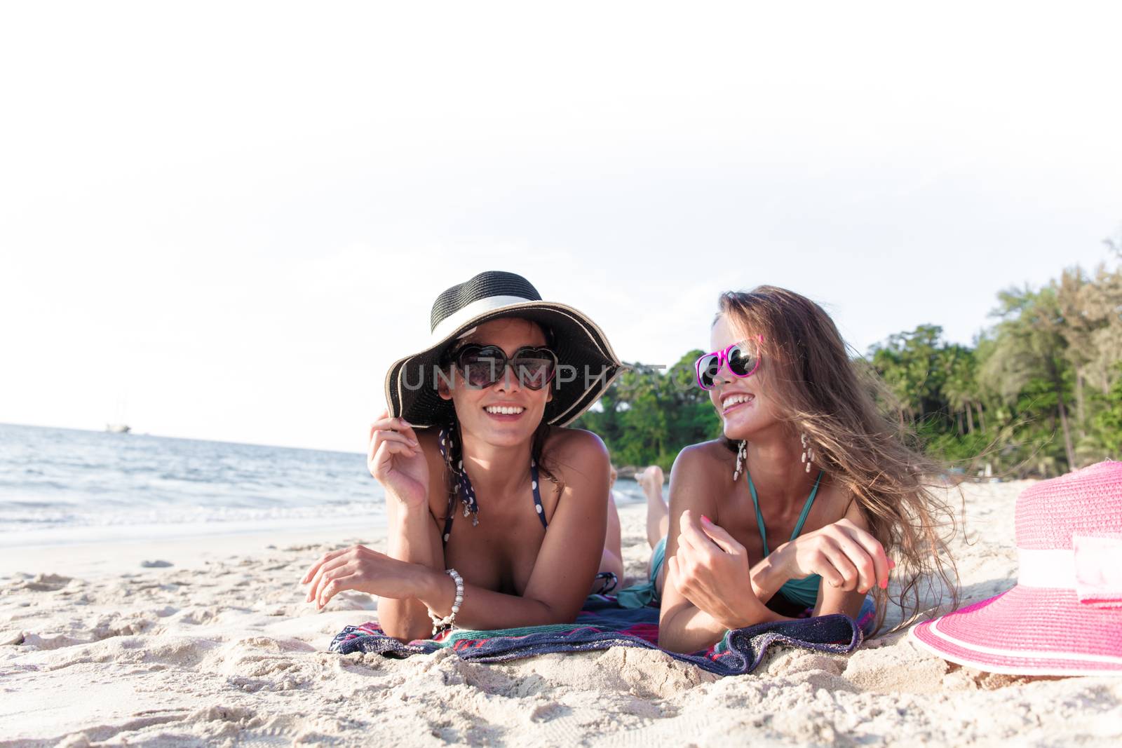 Beautiful young women in sunhats laying on beach