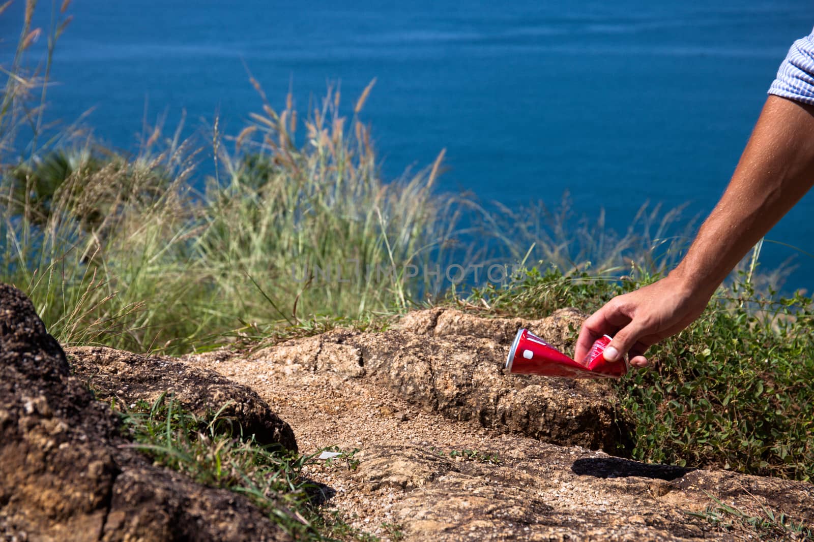 Man picking up litter can on rock at seaside