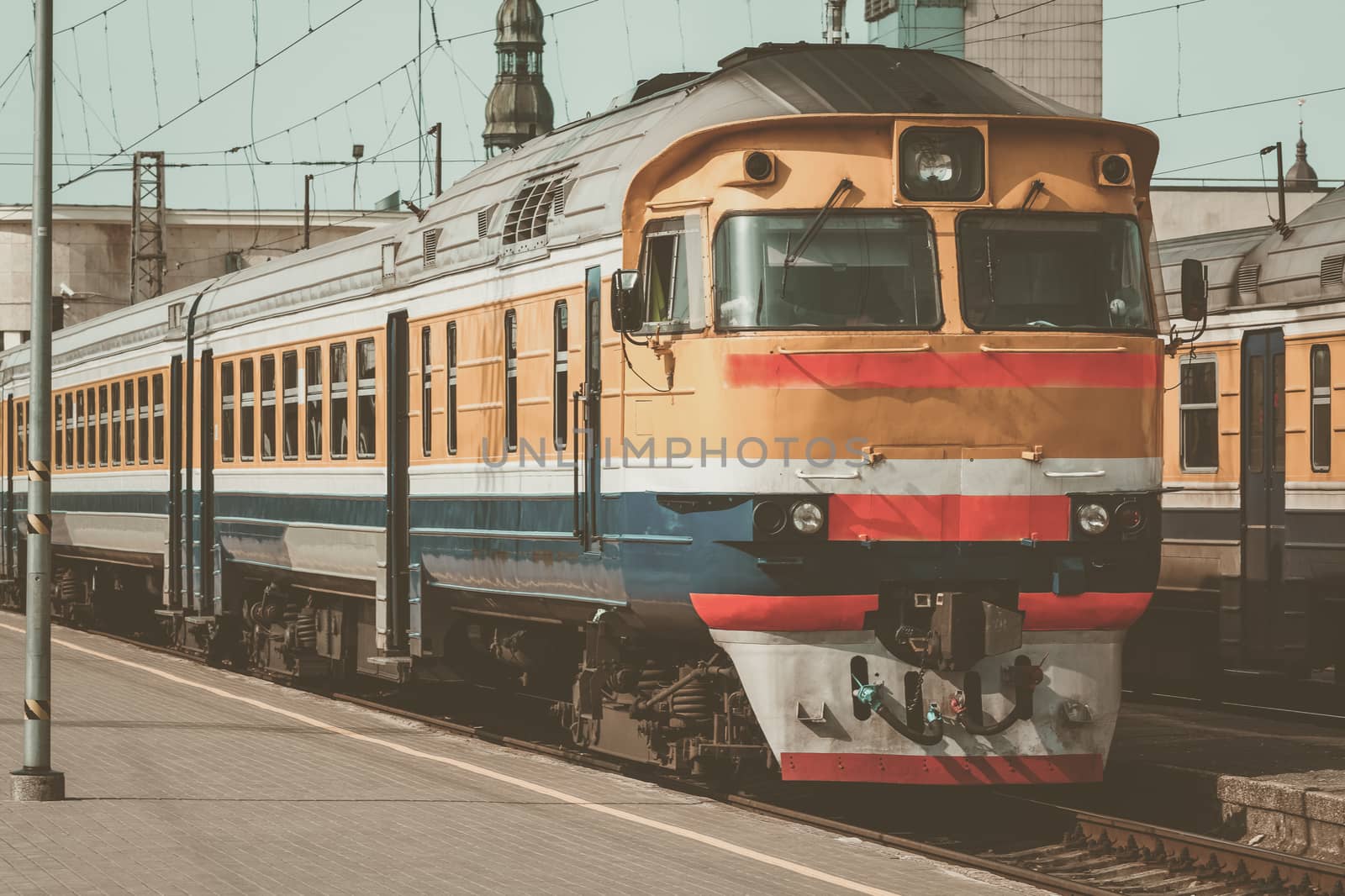 Old yellow passenger diesel train moving at the terminal