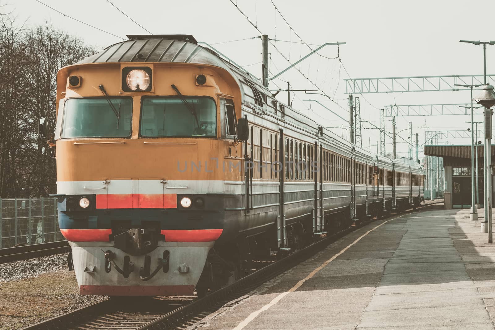 Old yellow passenger diesel train moving at the terminal