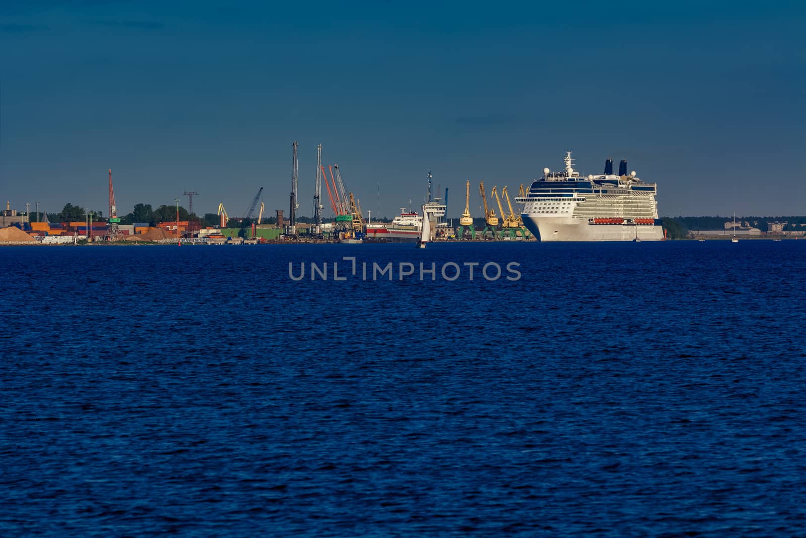 Giant white passenger ship moving past the port on a clear day