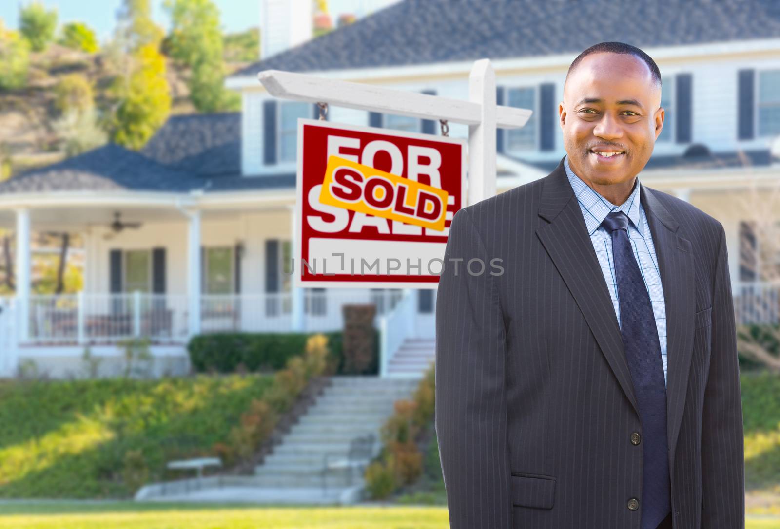 African American AgentIn Front of Beautiful Custom House and Sold For Sale Real Estate Sign.