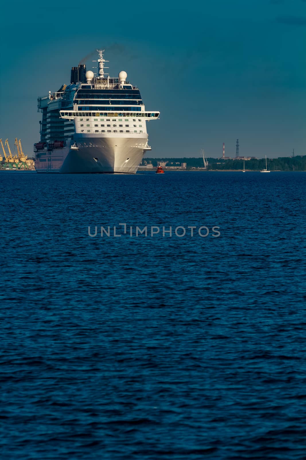 Giant white passenger ship moving past the port on a clear day