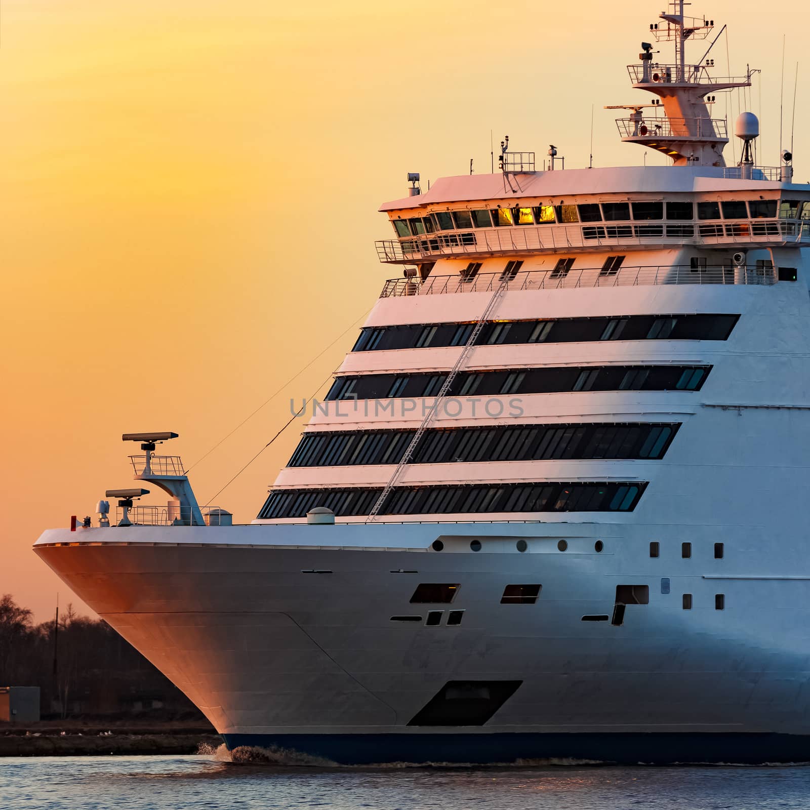 White passenger ship moving against the orange sunset sky