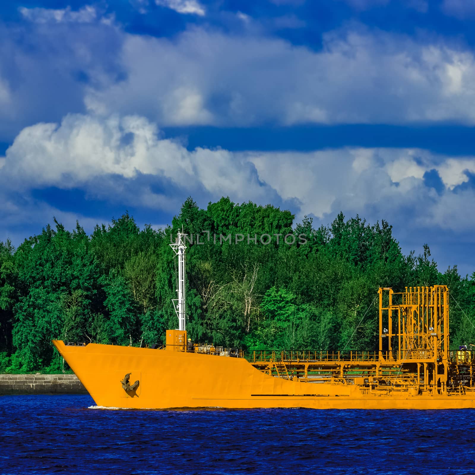 Yellow cargo tanker ship moving at the clear summer day