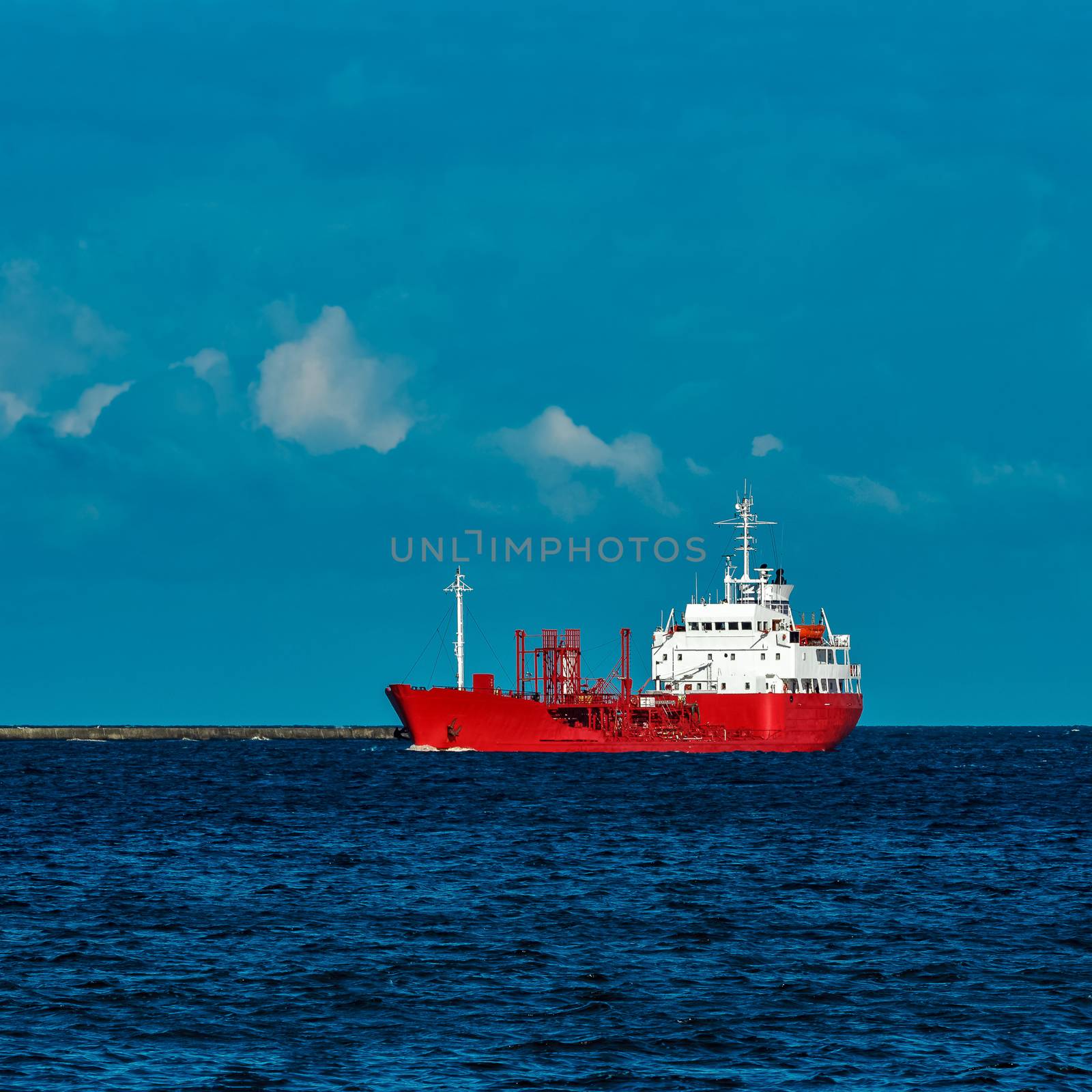 Red cargo tanker ship moving by the river