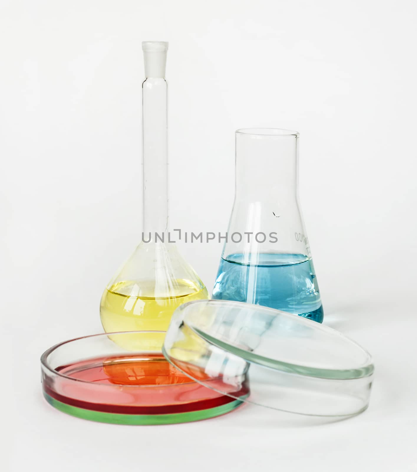 Miscellaneous laboratory glassware with colored solutions on a white background