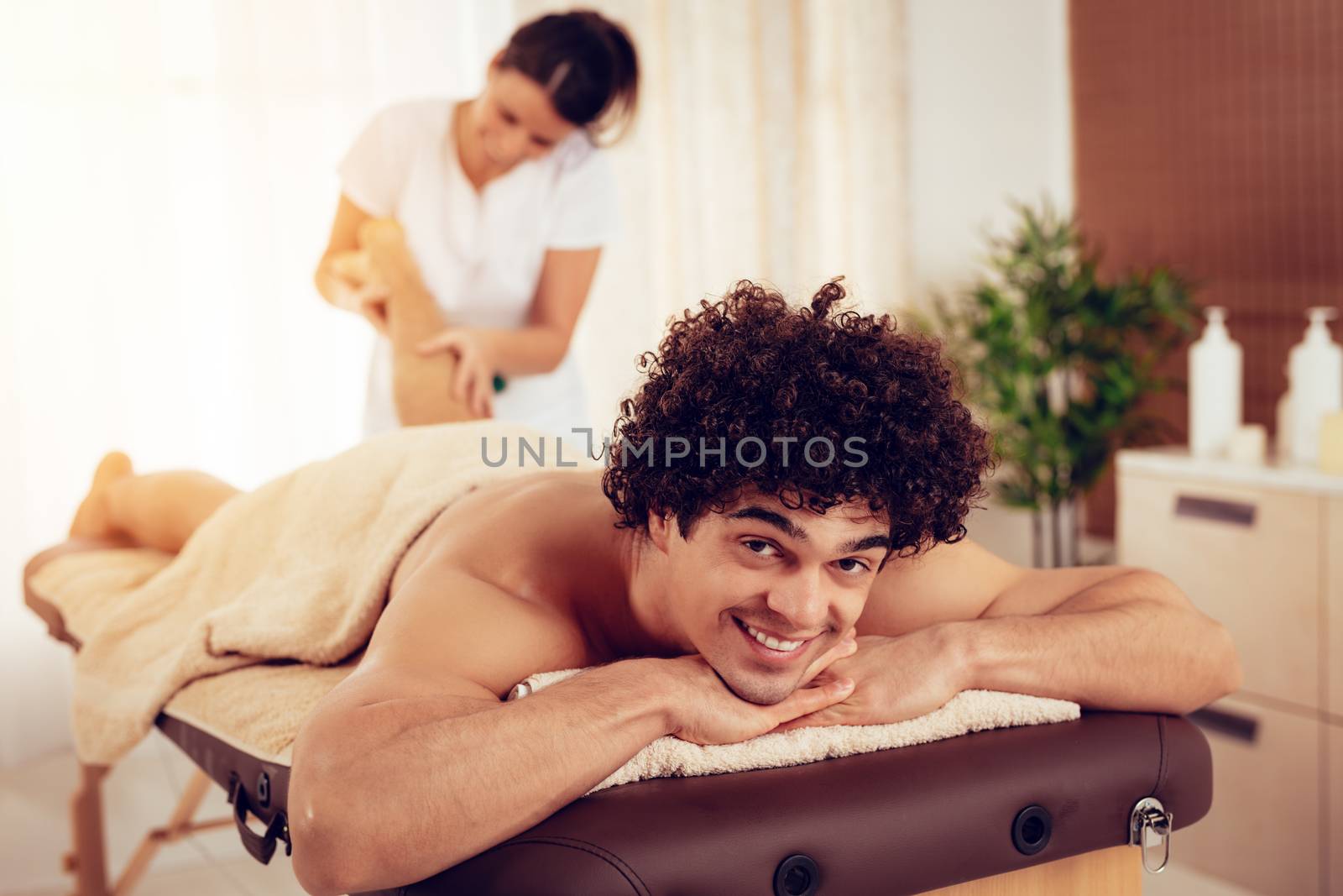Young massage therapist giving a relax massage to a male client.