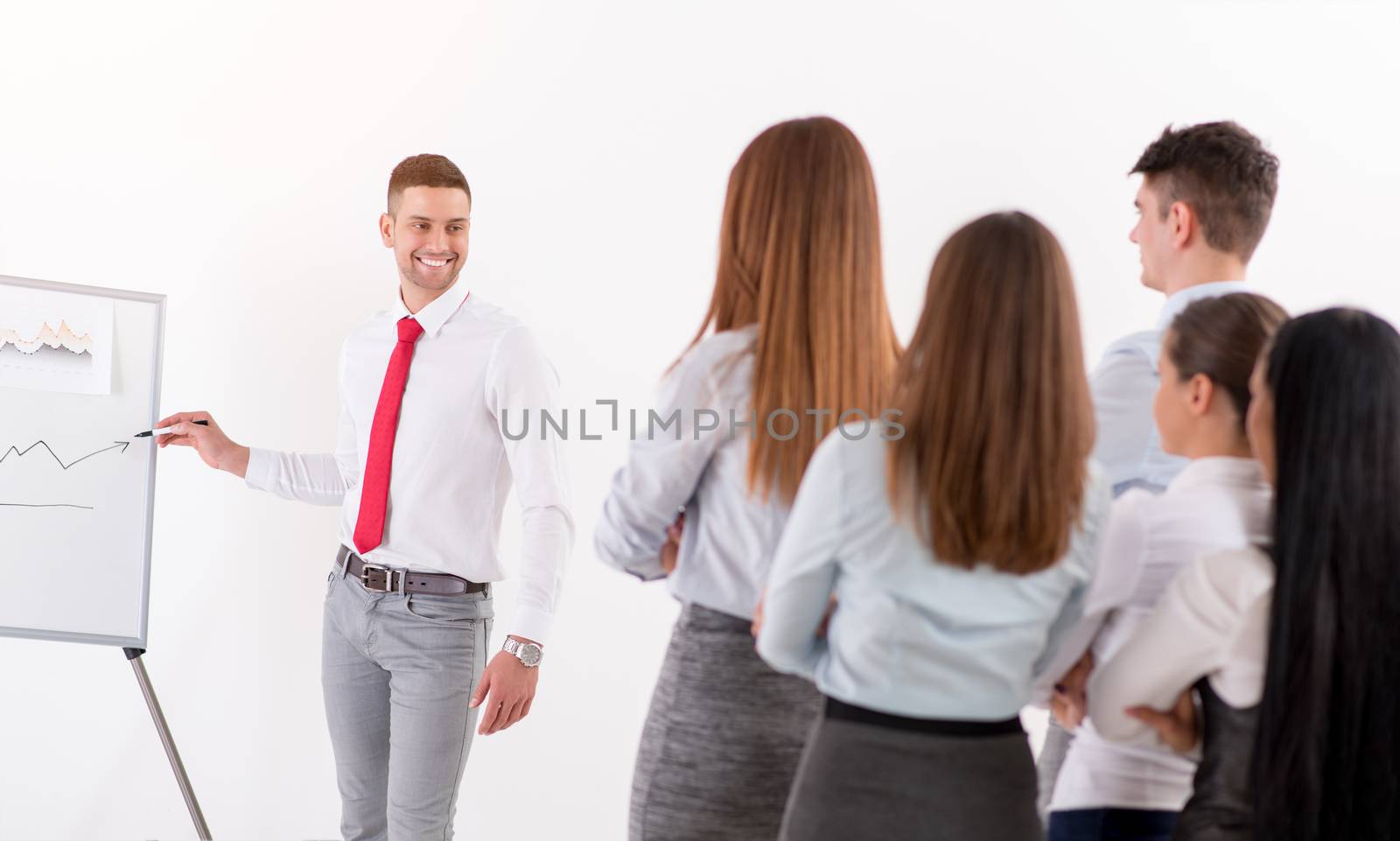 Businesspeople having meeting in a office. Young businessman standing  in front of flip chart and having presentation.