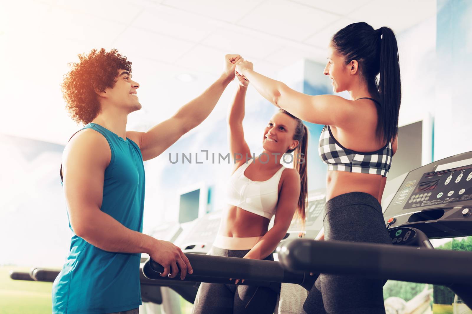 Three happy friends having a sports greeting afther workout at the gym. They are fist bump with smile on their face.