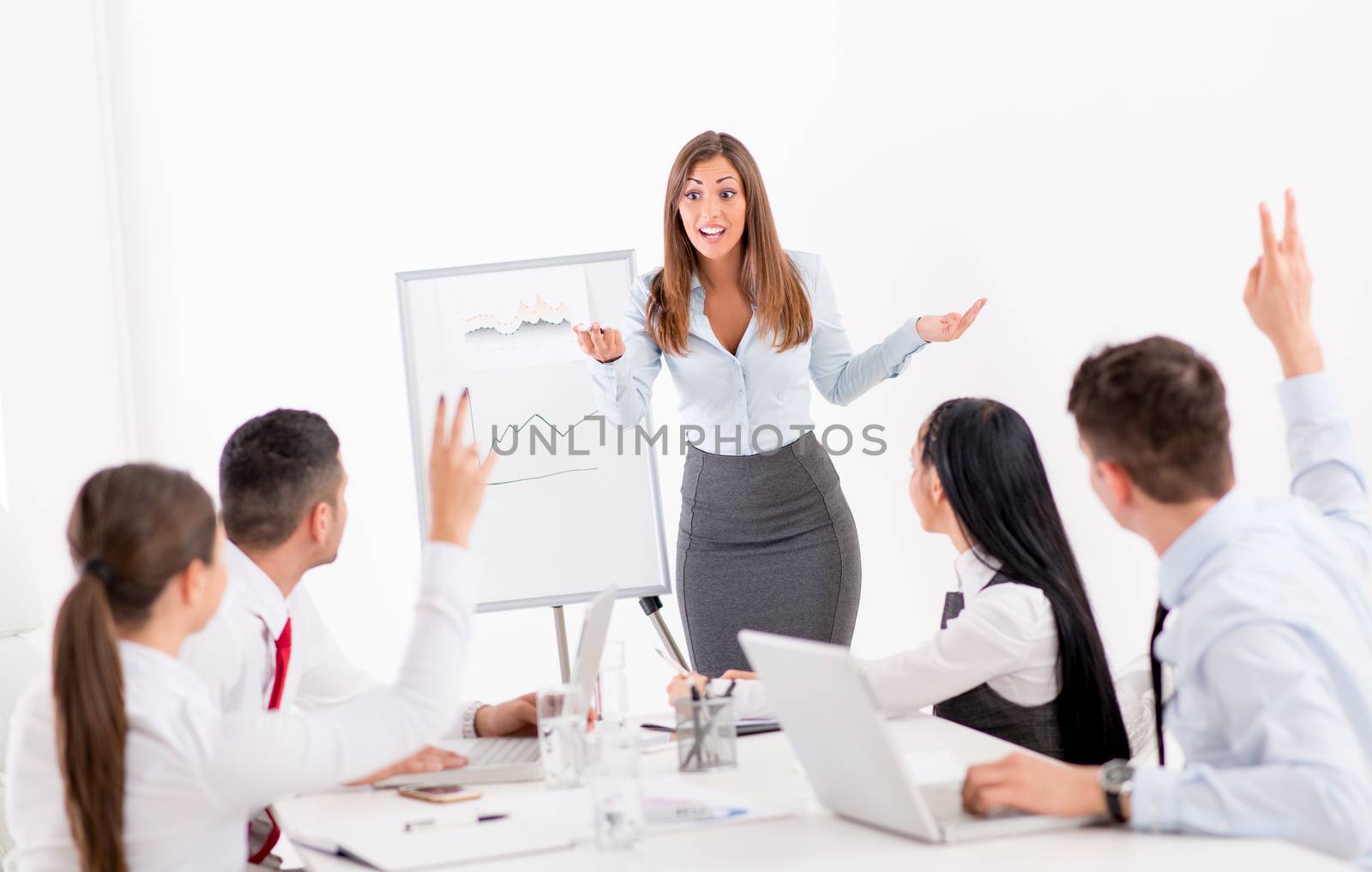 Businesspeople having meeting in a office. Young businesswoman standing  in front of flip chart and having presentation.