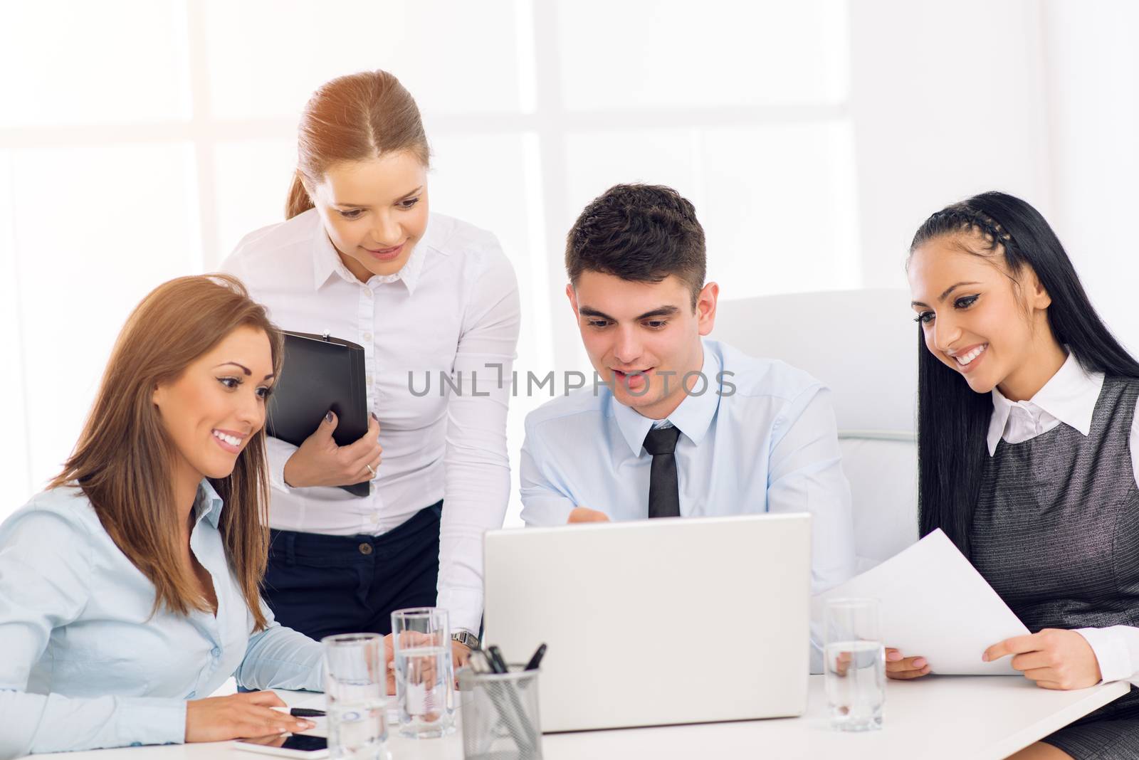 Successful young smiling colleagues working at laptop in the office.