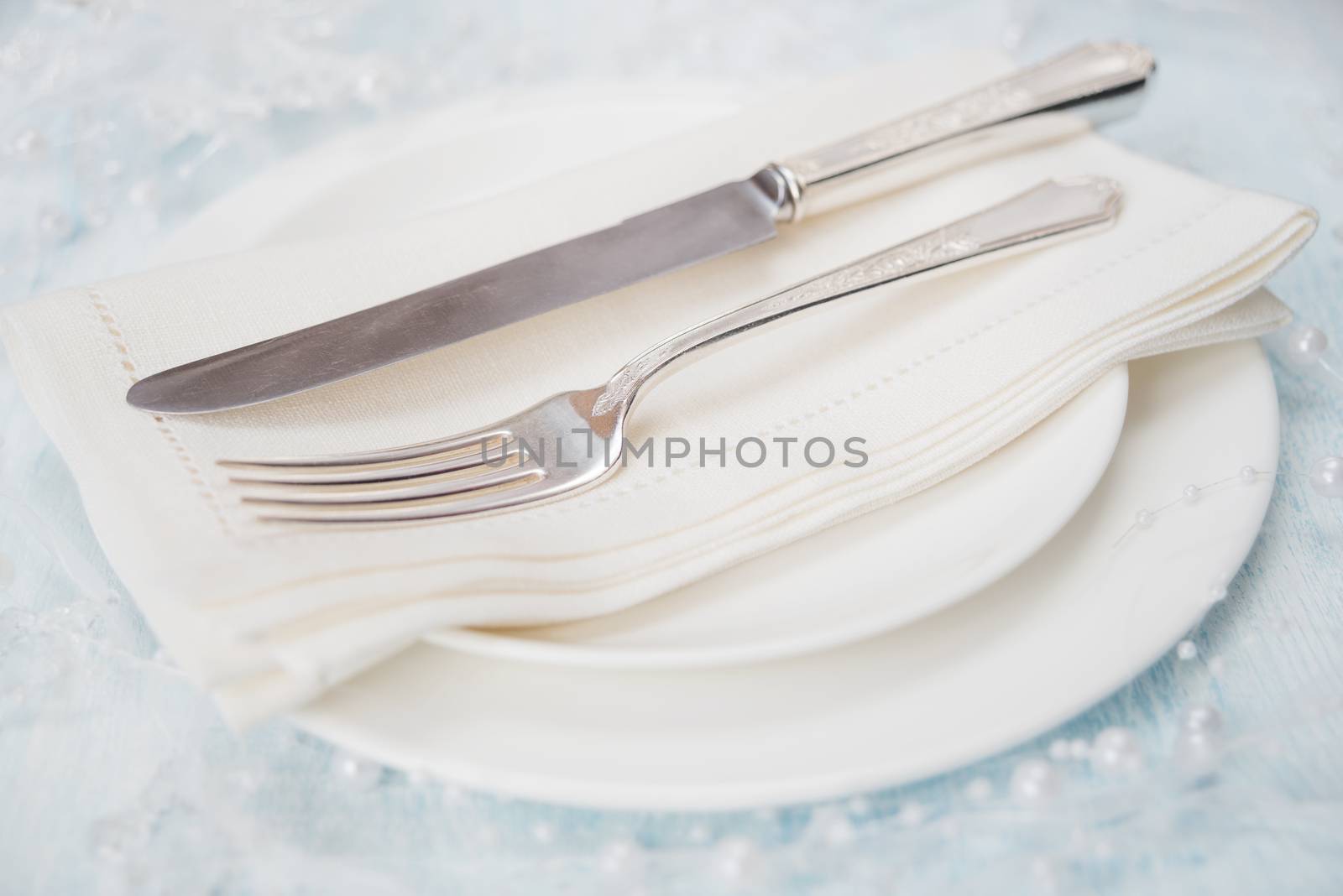 Festive table: silver knife and fork as well as a linen napkin are on the white porcelain plate