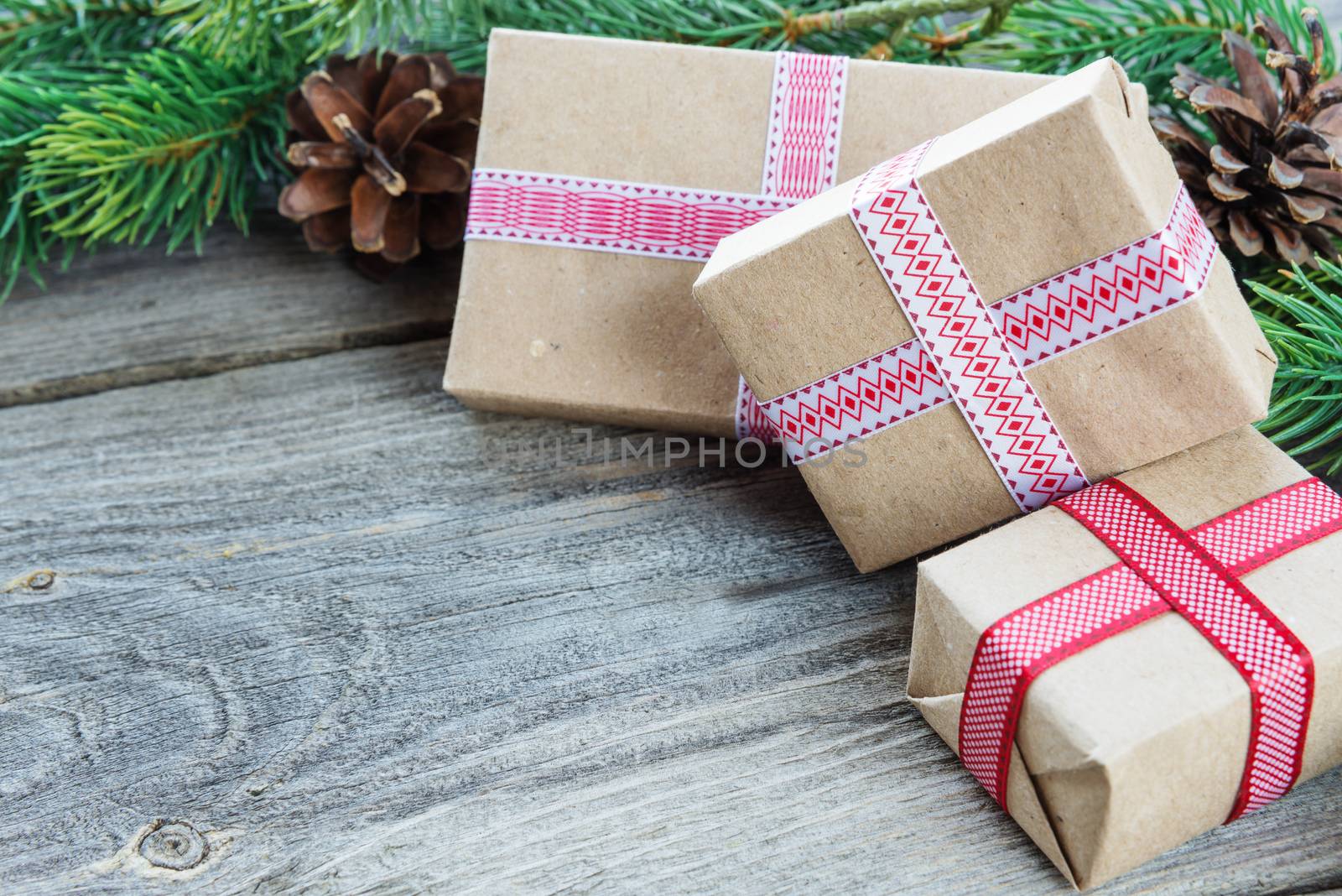 Christmas composition of pine cones, spruce branches and stack of gift boxes on the background of old unpainted wooden boards; with copy-space