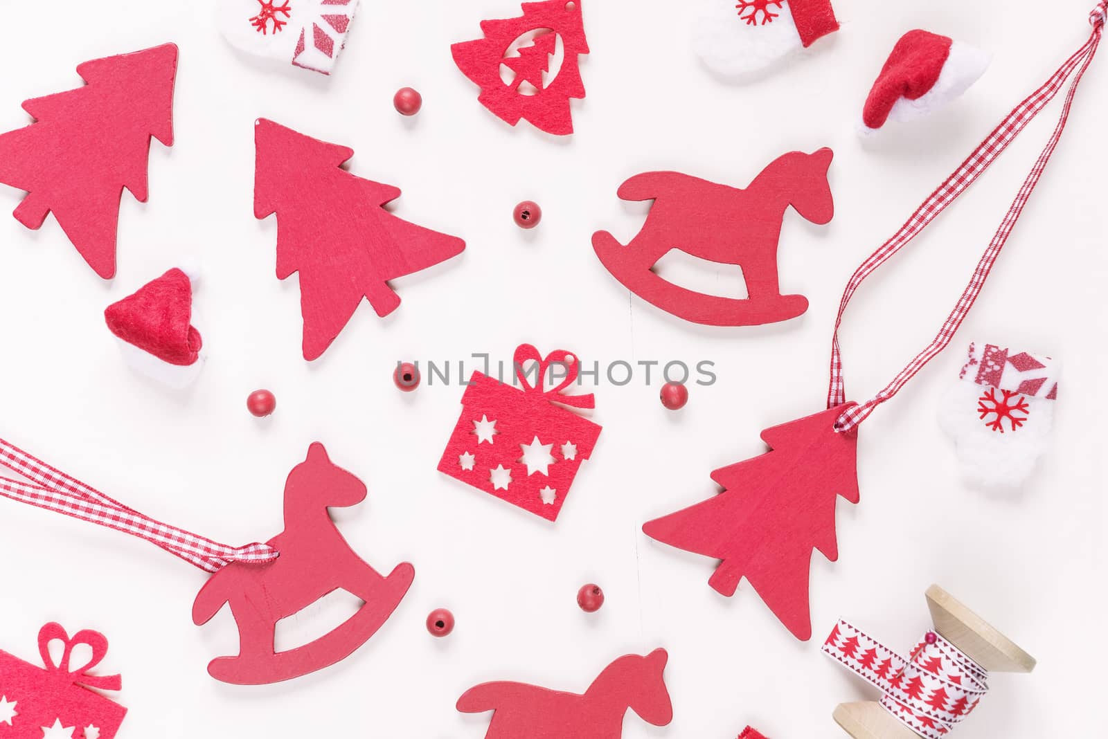 Christmas background composed of red christmas decoration: toy rocking horse, spruce, mittens, Santa's hat, checkered ribbon and gift boxes on white background. Christmas wallpaper. Flat lay composition for websites, social media, business owners, magazines,  bloggers, artists etc.