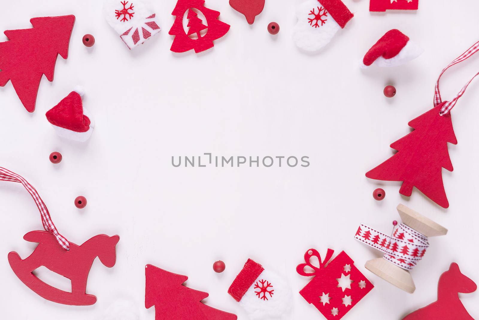 Christmas frame composed of red Christmas decoration: toy rocking horse, spruce, mittens, Santa's hat, checkered ribbon and gift boxes on white background. Christmas wallpaper for websites, social media, business owners, magazines,  bloggers, artists etc.