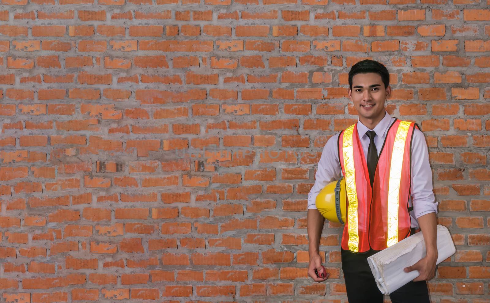 portrait of architect builder in front of  brick wall with copy space