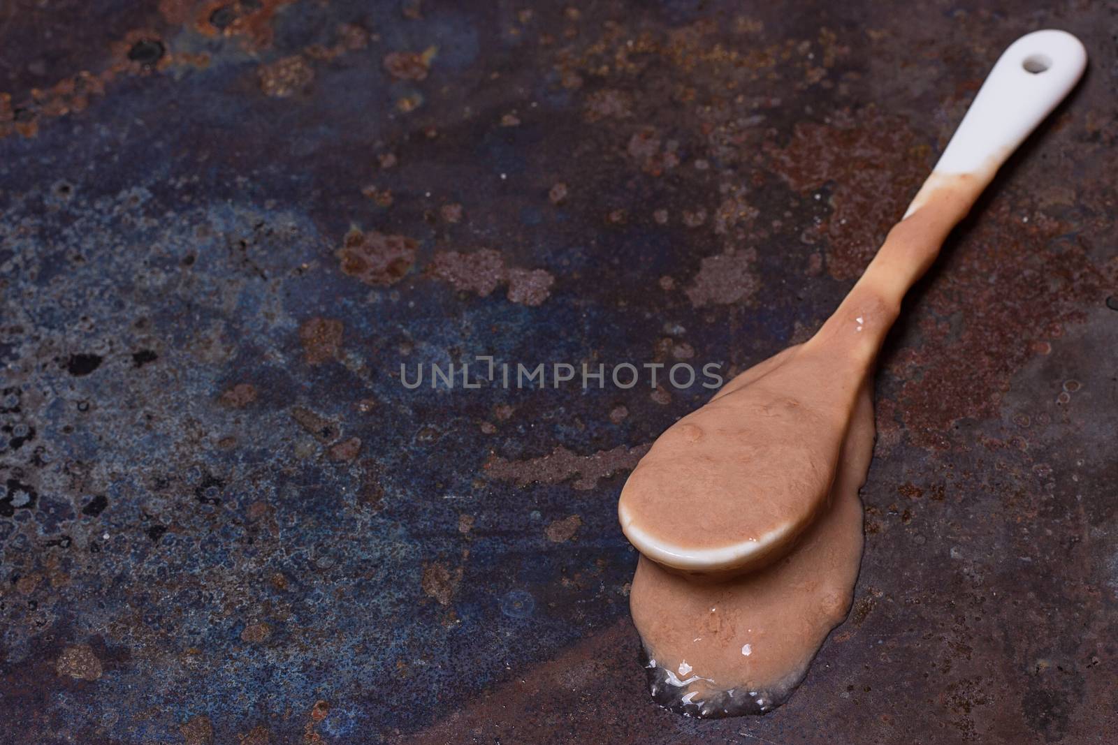 Spoon with melted ice cream on grunge background