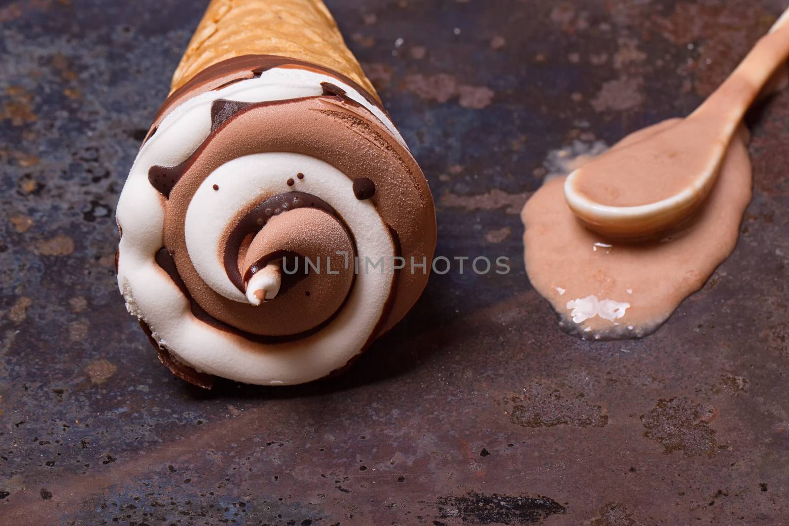 Wafer horn with chocolate ice cream and melted ice cream on grunge background