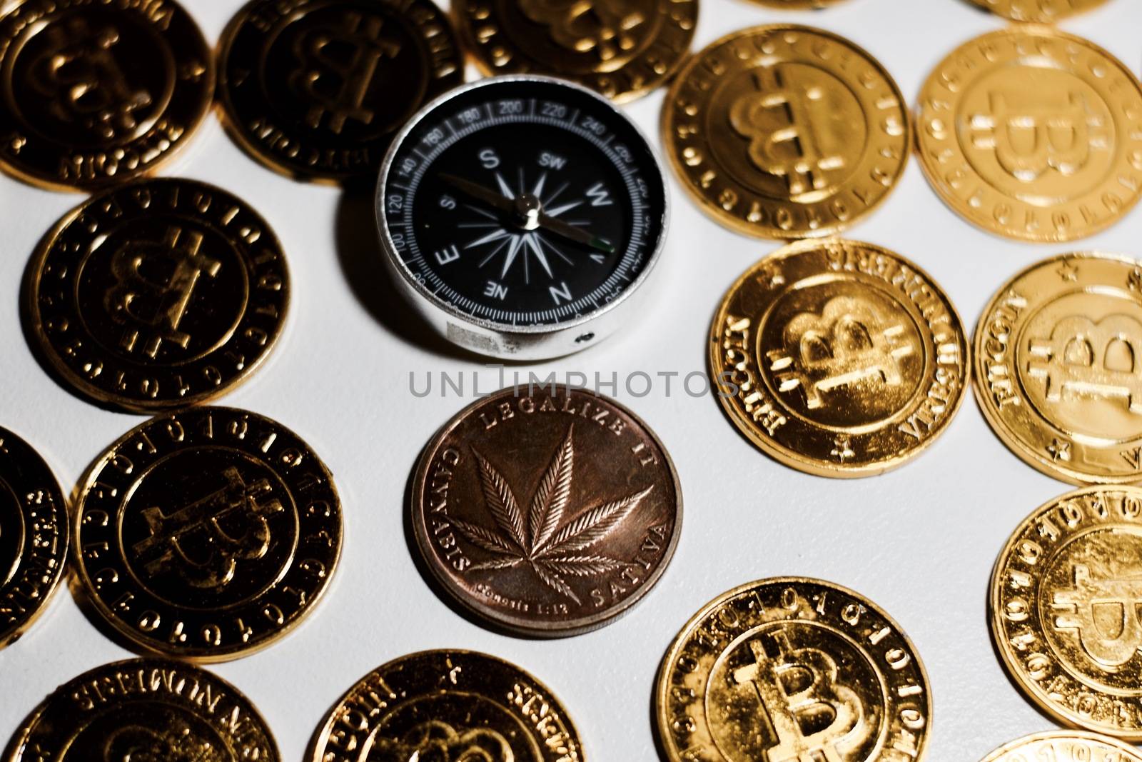 Brass physical marijuana metal coin on the gold bitcoin coins. Money weed concept.