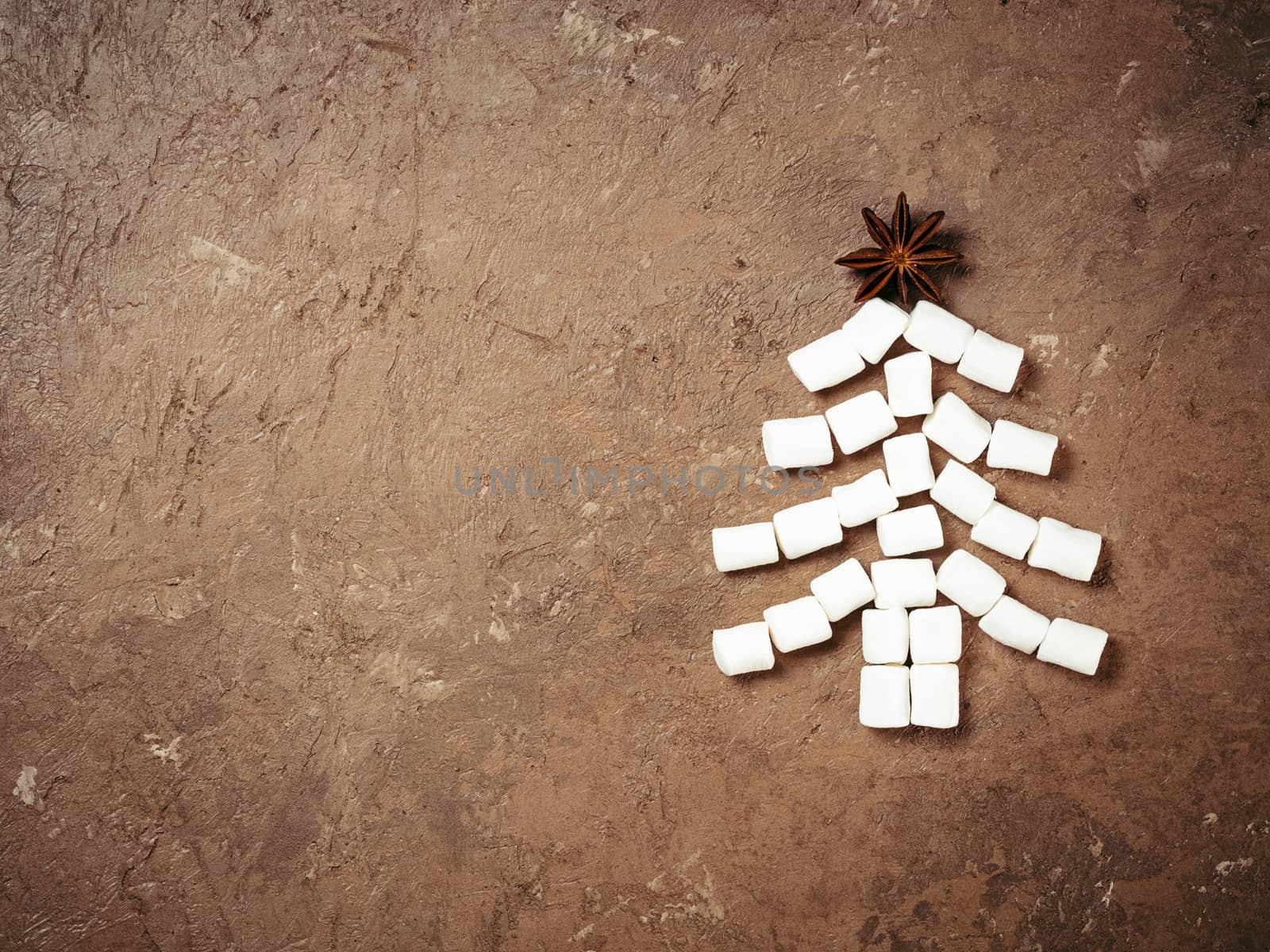 Christmas food and drink background. Christmas tree made from marshmallow and star anise on brown concrete textured background, Holiday and new year concept. Copy space. Top view or flat lay.