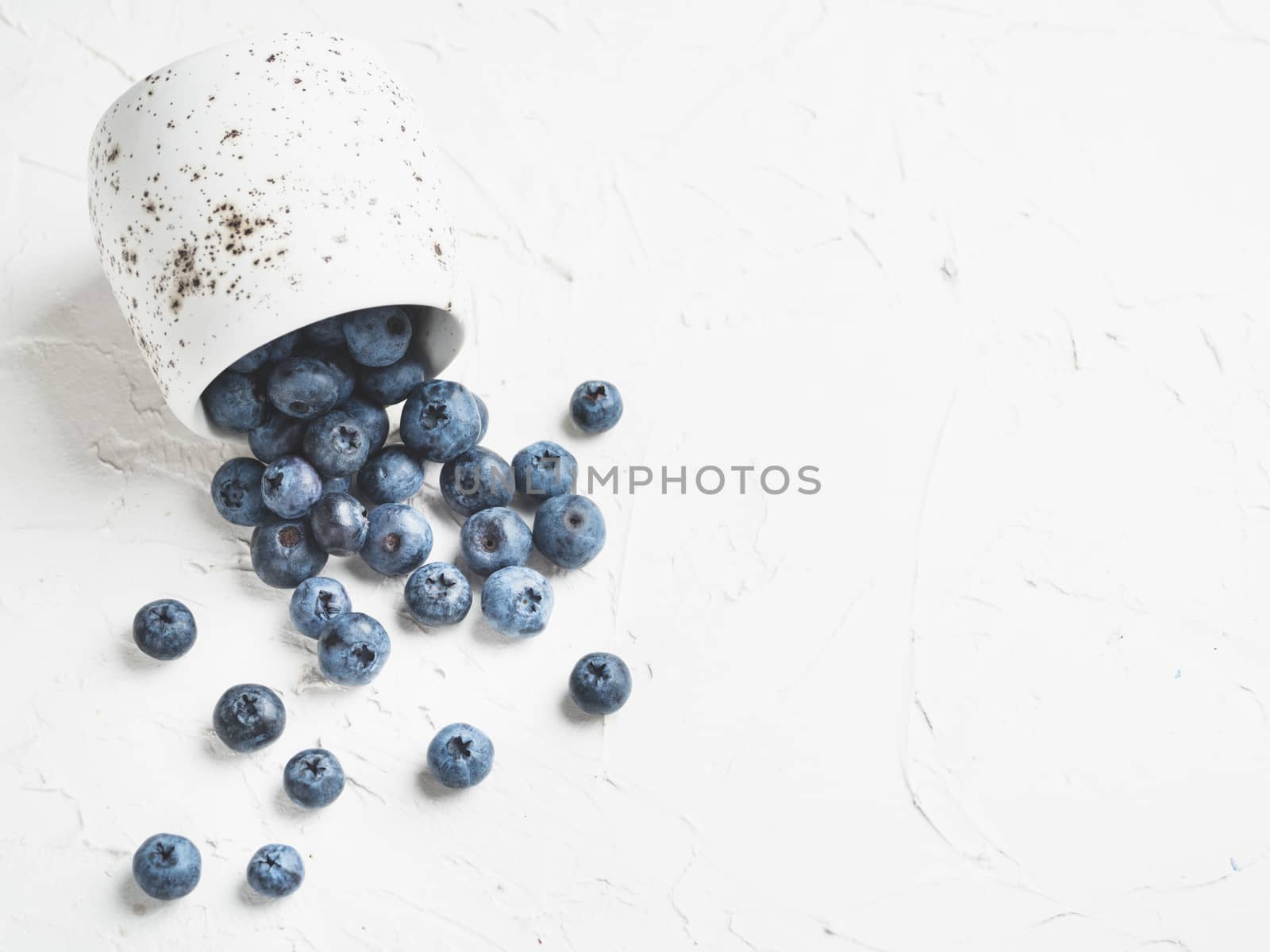 Blueberries on white concrete background. Blueberry border design. Fresh picked bilberries scattered close up. Copyspace. Closeup
