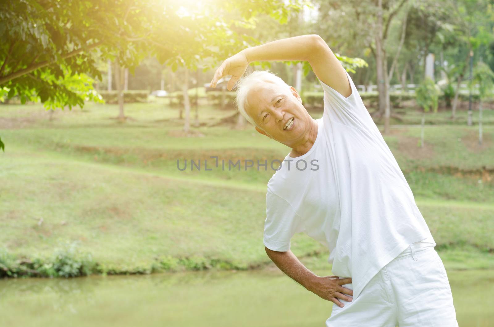 Portrait of healthy gray hair Asian old man stretching at outdoor park in morning.