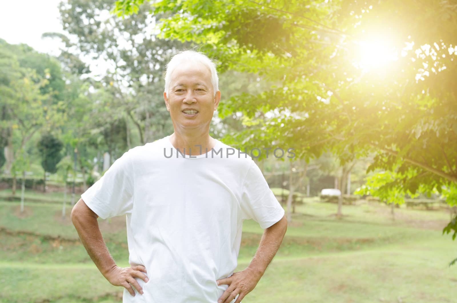 Portrait of healthy gray hair Asian old man smiling at outdoor park in morning.
