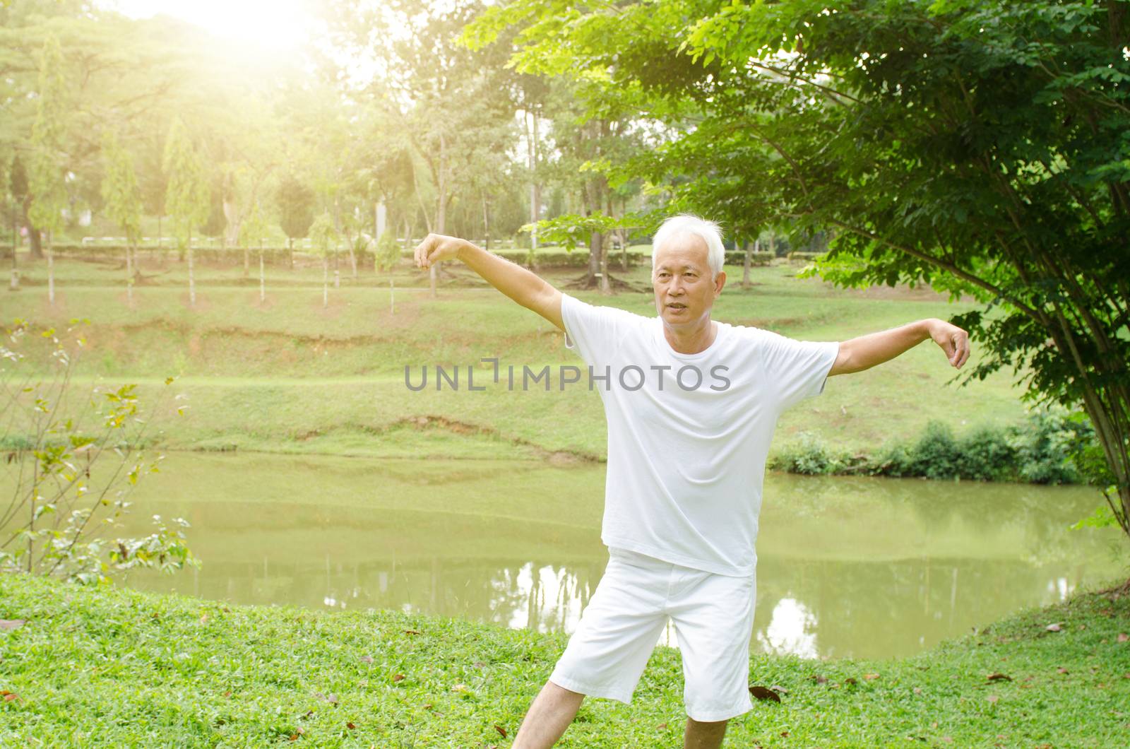 Portrait of healthy white hair Asian senior man practicing wushu at outdoor park in morning.