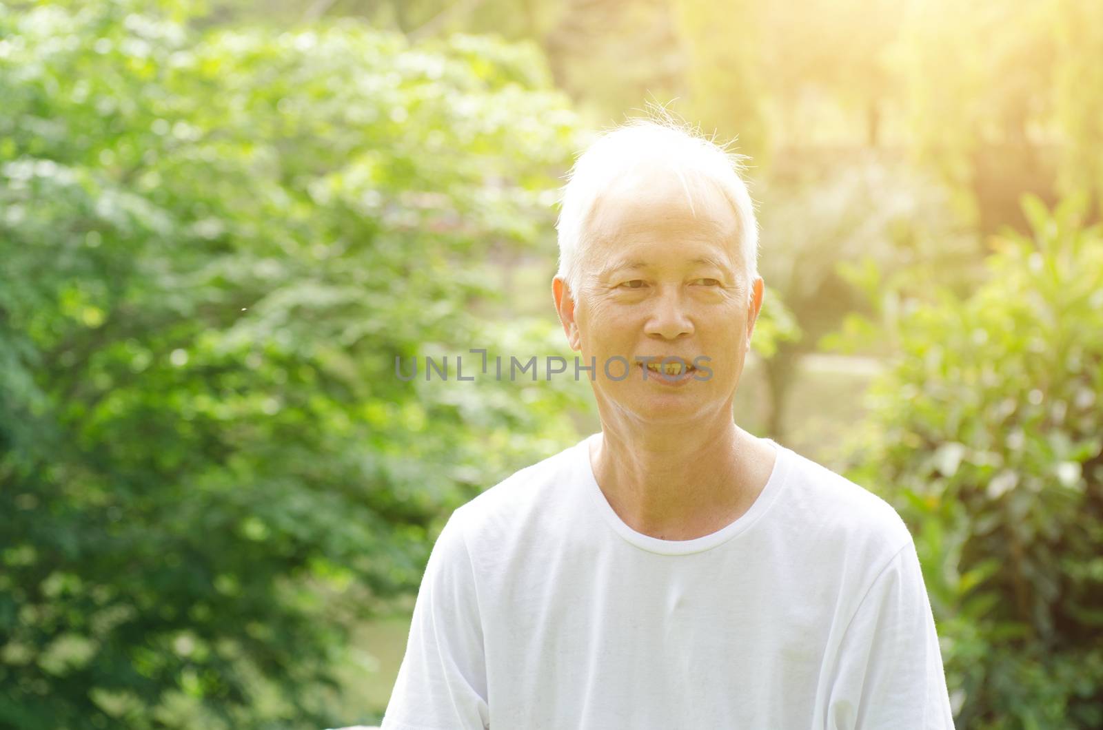 Portrait of white hair Asian senior adult man smiling, standing at outdoor park in morning. 