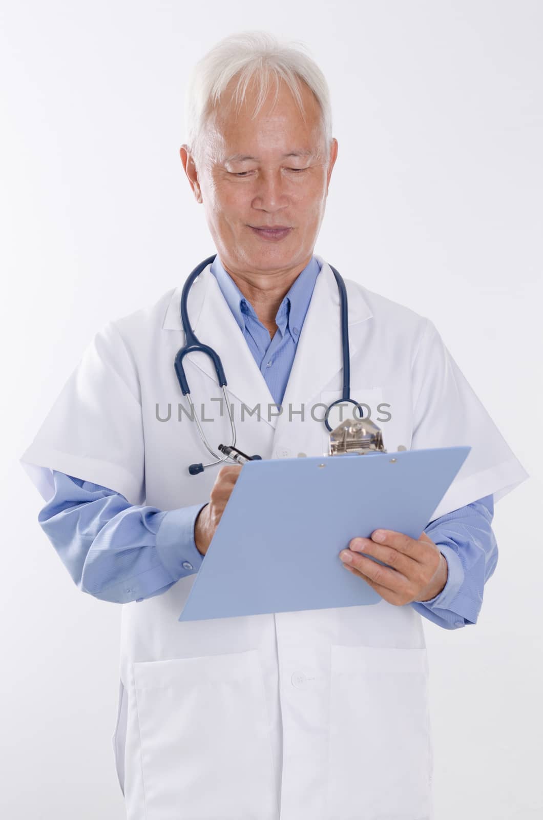 Portrait of Asian male medical doctor writing health report, standing isolated on white background.