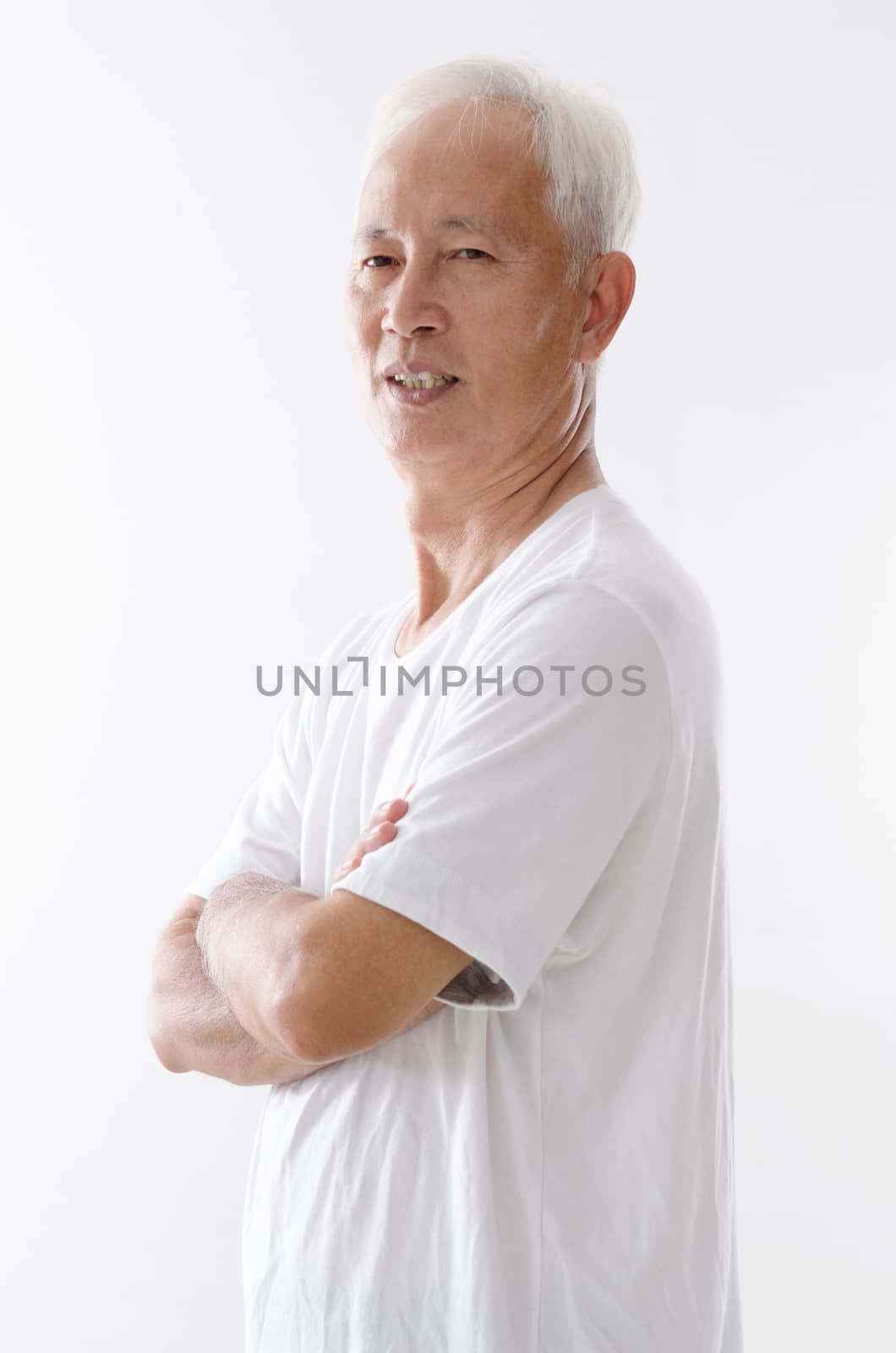 Portrait of side view old Asian man arms crossed standing isolated on white background.