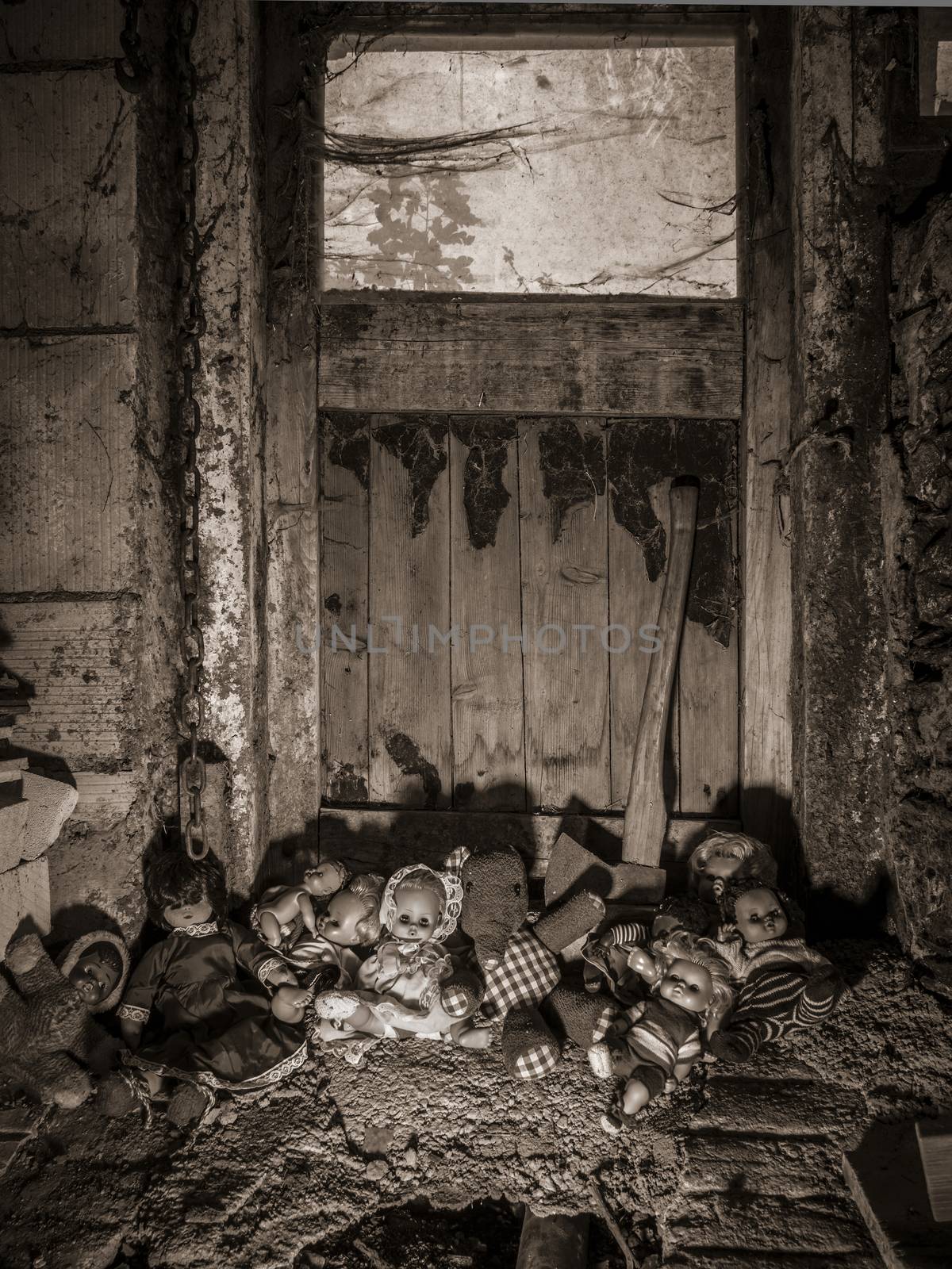 Photo of old dolls and an axe resting against an old barn door covered in spiderwebs and dust.
