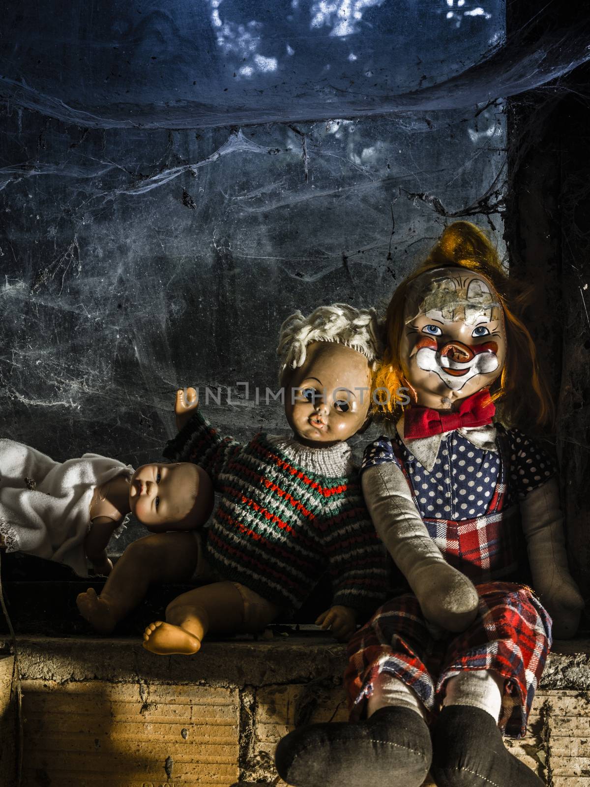 Photo of old dolls and an axe resting on an old window ledge covered in spiderwebs and dust.
