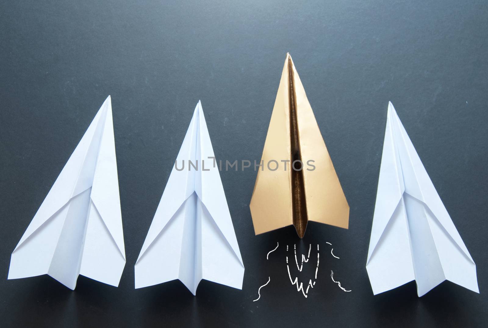 Gold paper plane standing out in a line 