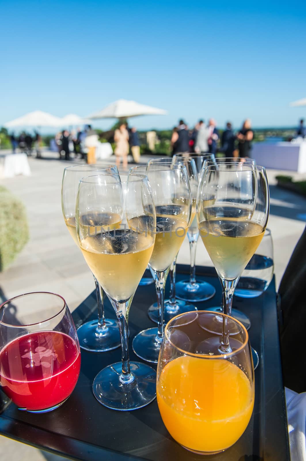 Waiter serving champagne and fruit juice on a tray, luxury diner