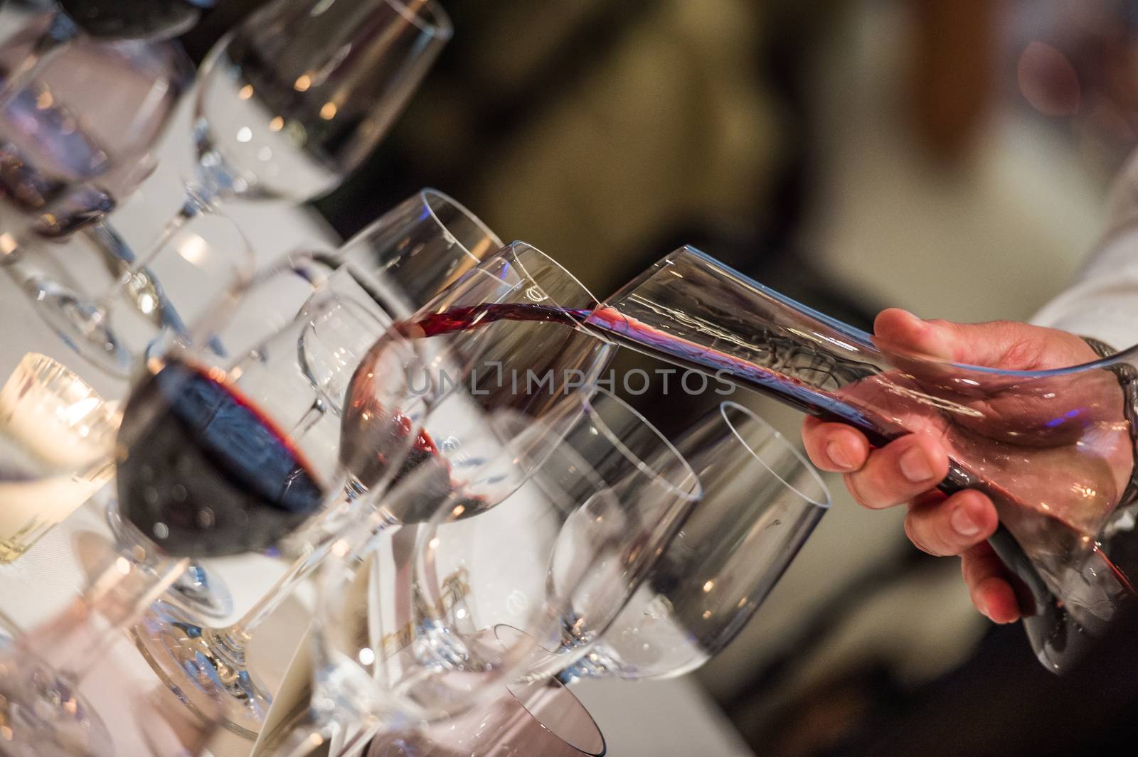 Sommelier pouring wine into glass from mixing bowl at luxury diner