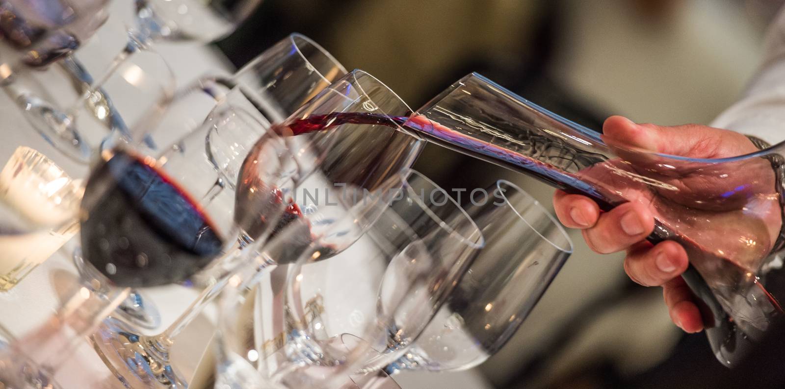 Sommelier pouring wine into glass from mixing bowl at luxury diner