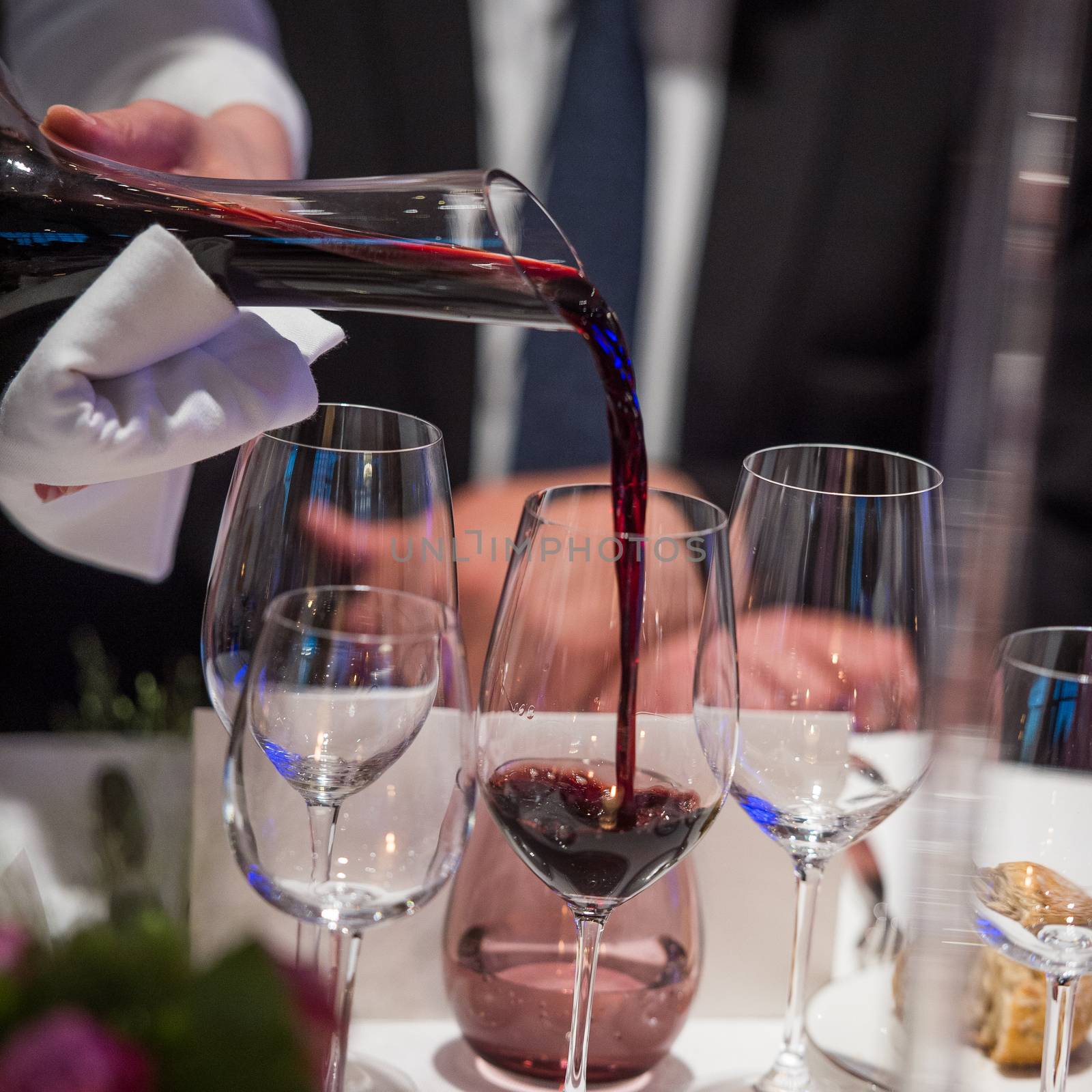 Sommelier pouring wine into glass from mixing bowl at luxury diner