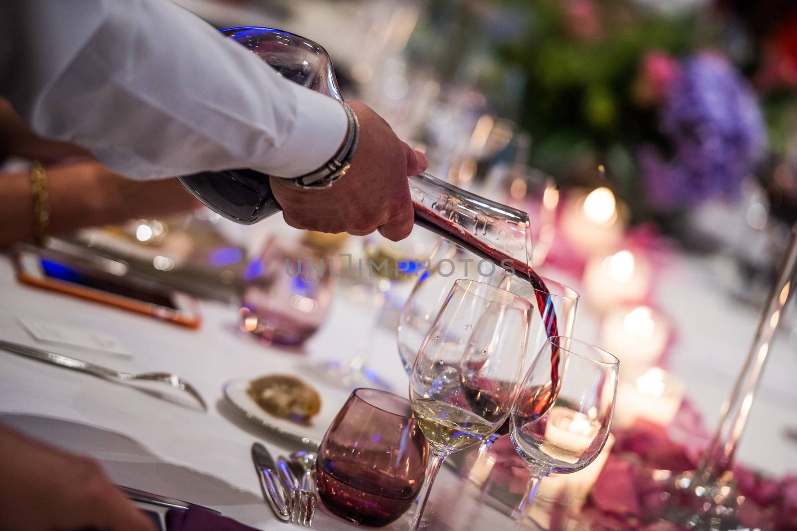 Sommelier pouring wine into glass from mixing bowl at luxury diner