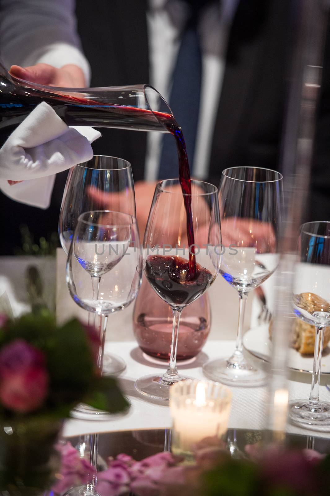 Sommelier pouring wine into glass from mixing bowl at luxury diner